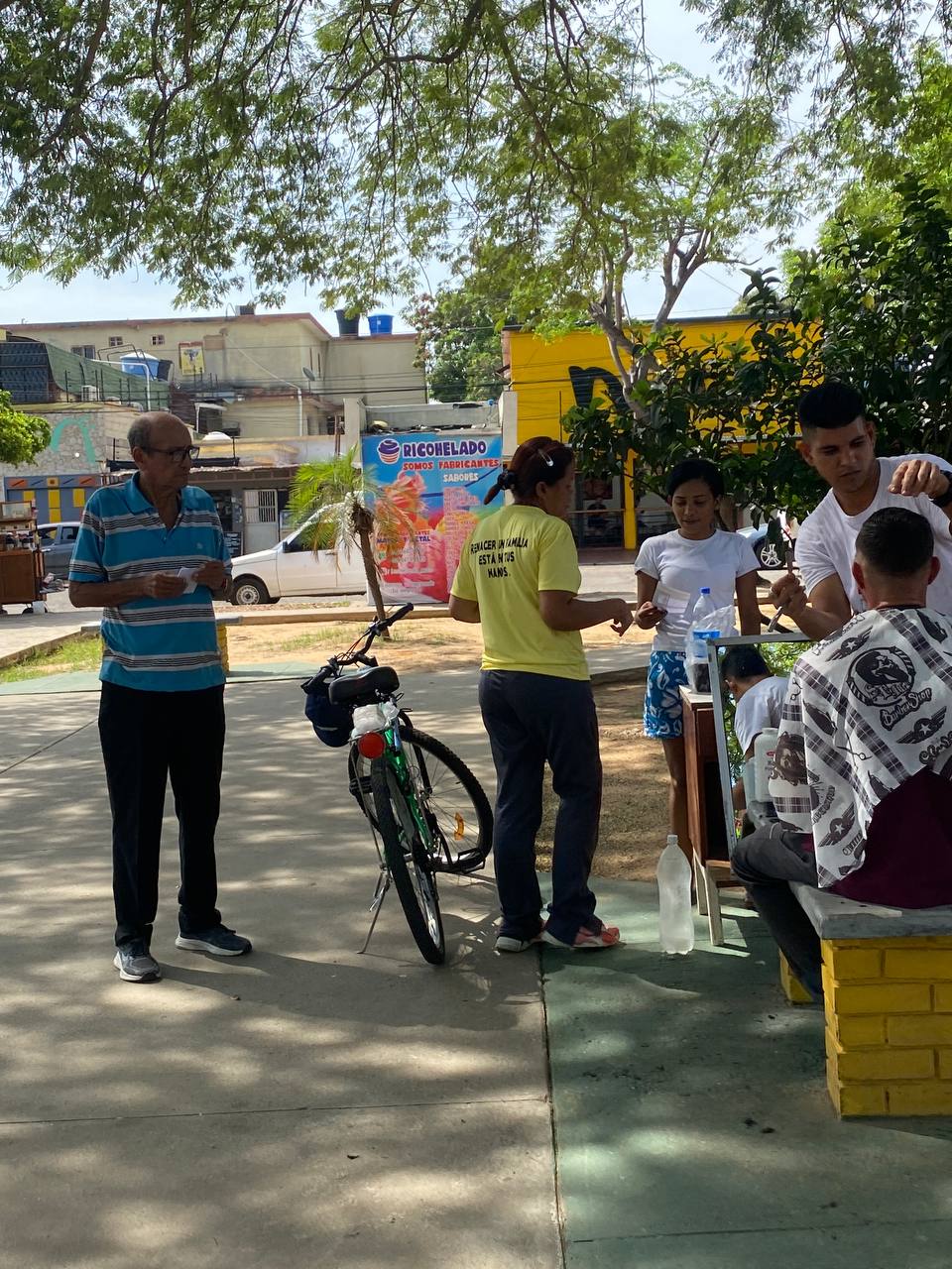 man wearing a black jacket, white shirt, blue jeans, and brown boots, playing a white electric guitar while sitting on an amp
